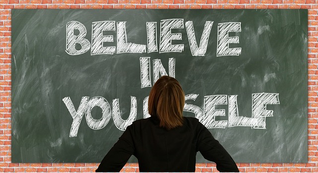 tutor standing in-front of chalk board which says believe in yourself